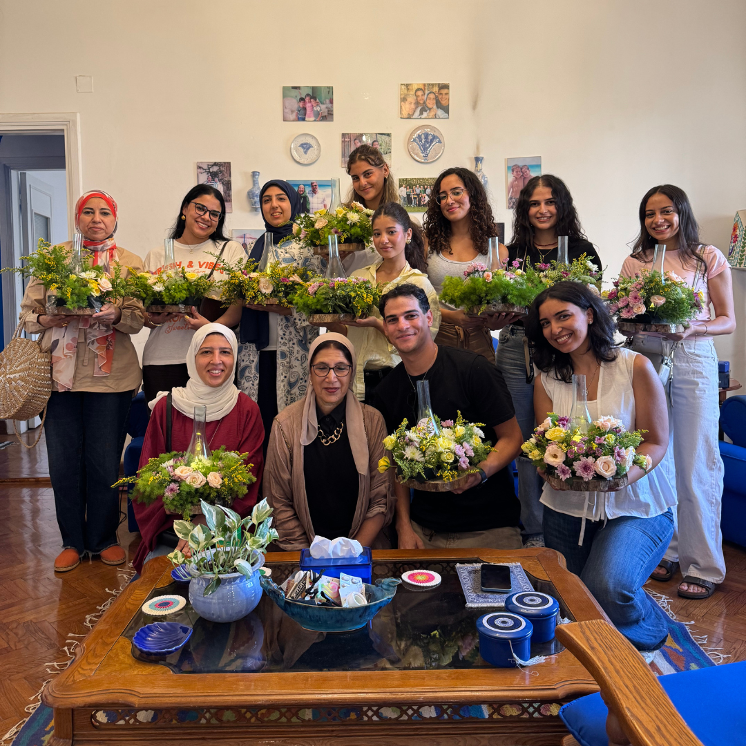 Group of people posing together with floral arrangements in a room. Flower arrangement workshop in Cairo