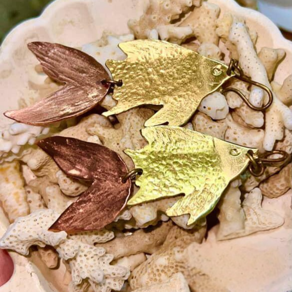 Gold and bronze leaf-shaped earrings on a textured surface